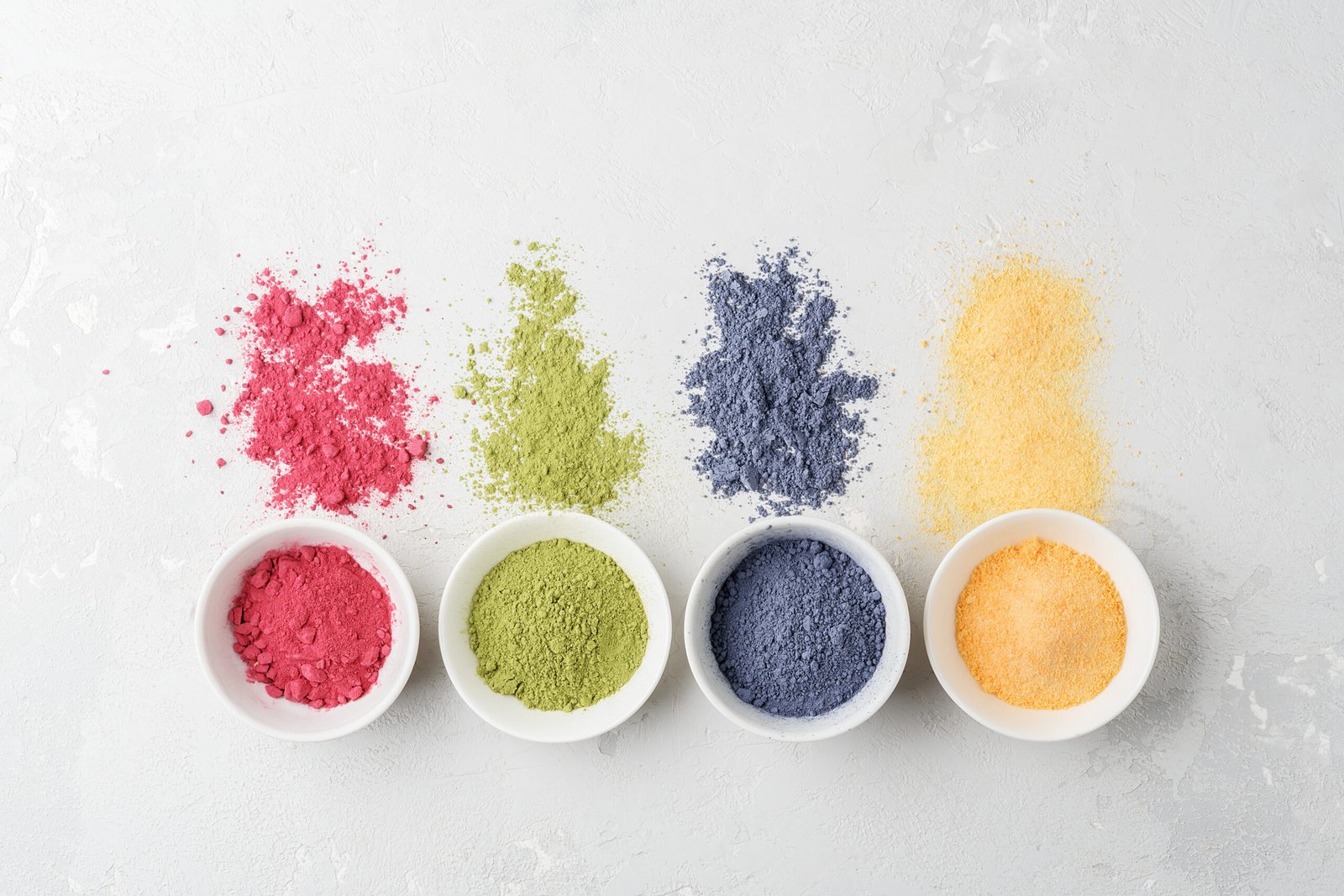 bowls of multicolored matcha tea powder on a concrete background